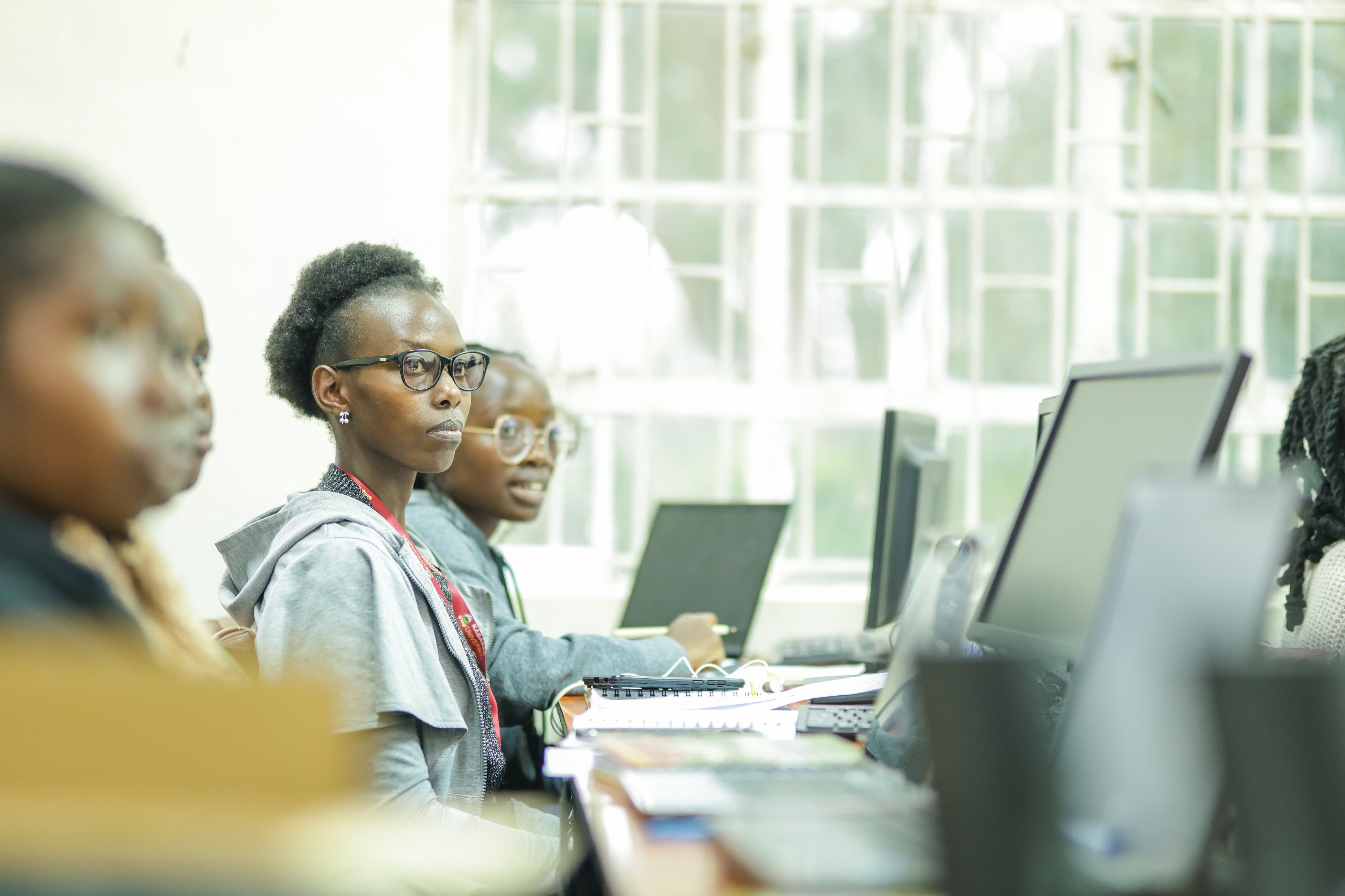 A group of young women collaborating around a computer screen